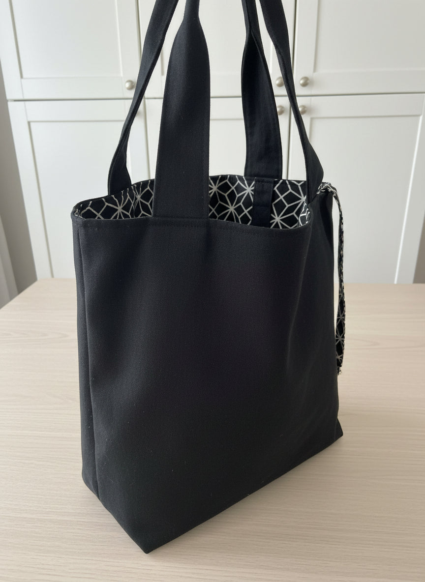 Close-up of a black garment with a geometric patterned fabric underneath