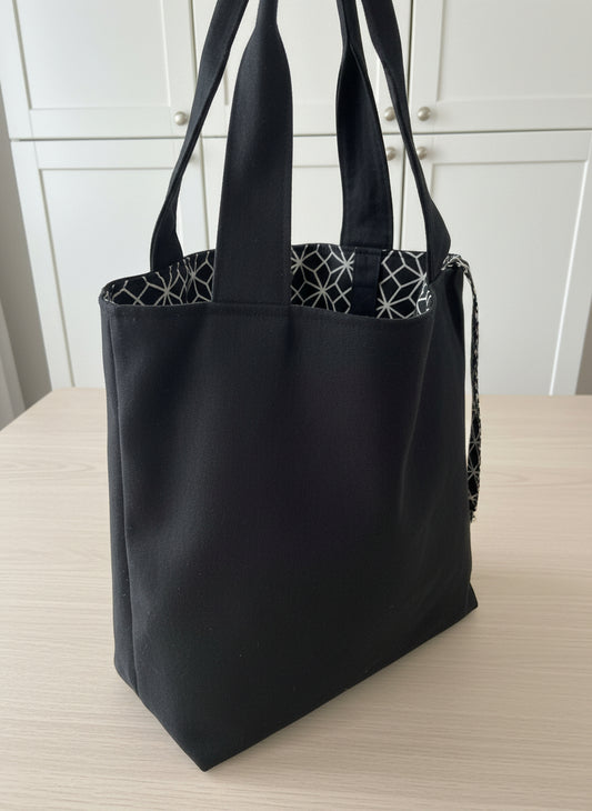 Close-up of a black garment with a geometric patterned fabric underneath