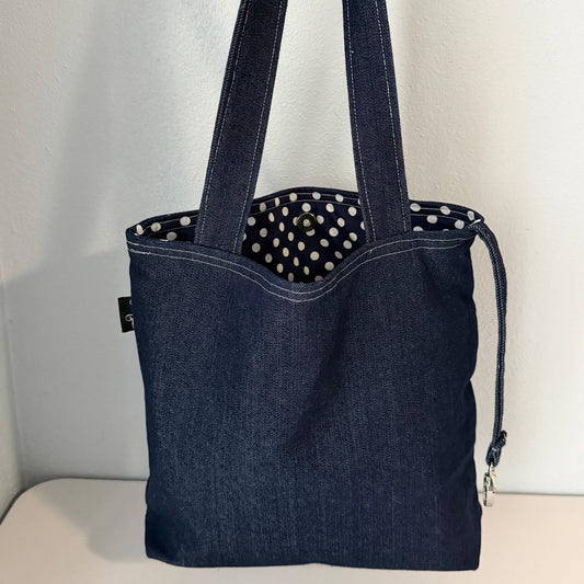 Blue denim tote bag with polka dot interior on a white background